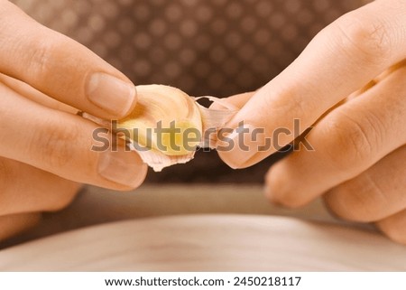 Woman peeling fresh garlic at table, selective focus