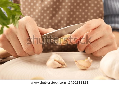 Woman peeling fresh garlic at table, closeup