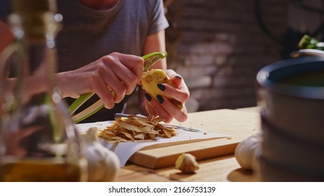 Woman Peeling Ginger And Vegetables For Cooking On Kitchen Table. Closeup Hands. Cosy Dark Room. Real, Authentic Cooking.