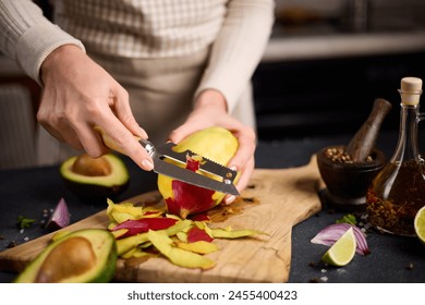 Woman peeling mango on a wooden cutting board at domestic kitchen - Powered by Shutterstock