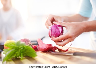 Woman peeling red onion in kitchen - Powered by Shutterstock