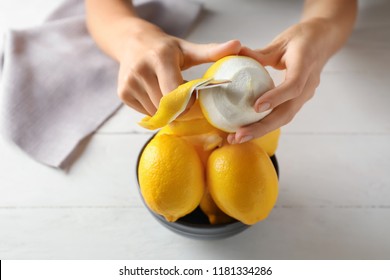 Woman peeling ripe lemons at white wooden table, closeup - Powered by Shutterstock