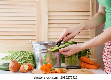 Woman Peels Cucumber And Throws Vegetable Peeling, Scraps In Compost Bucket. Food Garbage Reduce. Sorting Of Household Waste, Composting. Zero Waste Lifestyle. Recycling Of Food Waste In Trash-can