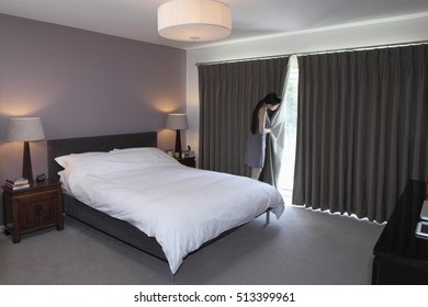 Woman peeping behind bedroom curtain - Powered by Shutterstock