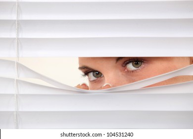 Woman Peering Through Blinds