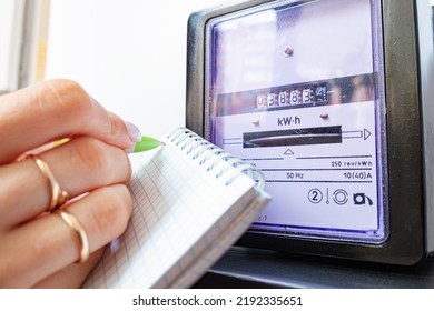 Woman with pen and notepad writes the electricity meter readings at home. Payment of utility services. - Shutterstock ID 2192335651