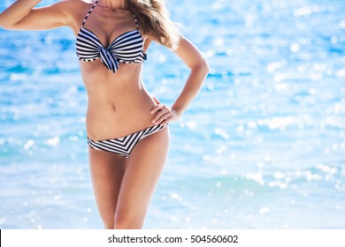 Woman with perfect body in bikini over blue sea background
