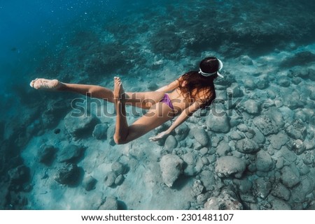 Woman with perfect body dive to the deep in tropical blue sea. Snorkeling with beauty lady in Hawaii