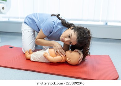 Woman performing CPR on baby training doll with one hand compression. First Aid Training - Cardiopulmonary resuscitation. First aid course on cpr dummy. - Powered by Shutterstock