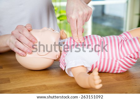 woman performing CPR on baby training doll with one hand compression