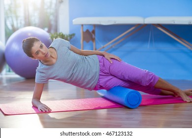 Woman Performing Exercise Using Foam Roll In The Clinic