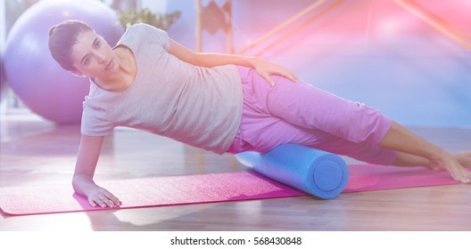 Woman Performing Exercise Using Foam Roll In Clinic