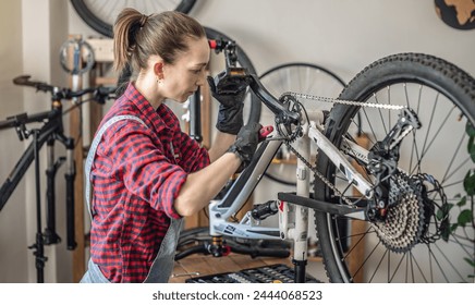 A woman is performing maintenance on mountain bike. Concept of fixing and preparing the bicycle for the new season - Powered by Shutterstock