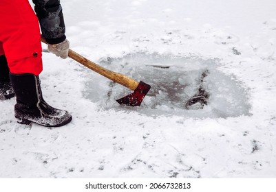 Woman Person Making Ice Hole With An Ax In The Winter For Ice Bath And Taking Water.