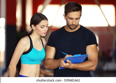 Woman With Personal Trainer Preparing Training Plan In Gym