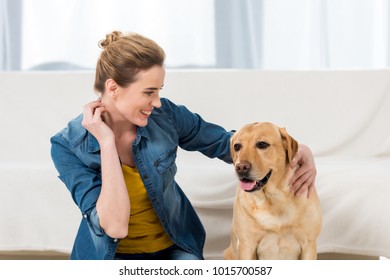 woman petting her labrador dog at home