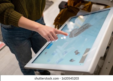 Woman with phone configuring furniture at the self-service desk in the store - Shutterstock ID 1620545203