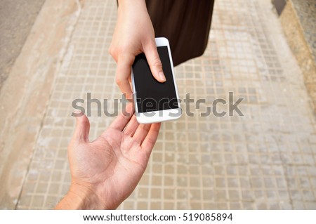 woman with a phone in his hand  return it to its owner at the city street. Concept of loan from a phone to help someone.
