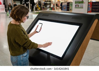 Woman With Phone Uses Self-service Kiosk In The Shopping Mall