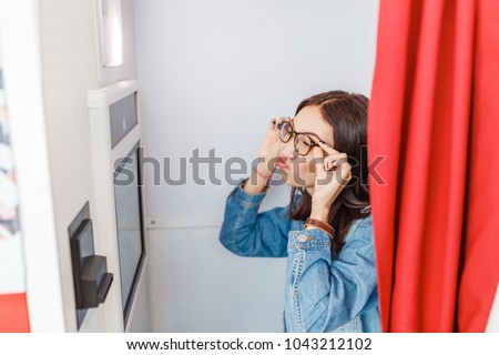 A woman is photographed and amused in a photo booth, making istant selfie photos for fun or for passport and documents