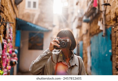 woman photographer with a camera takes pictures outdoors. A young female photographer aims the lens and enjoys the process of shooting. travel to Arab countries. travel and vacation. - Powered by Shutterstock