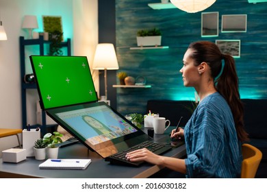 Woman photographer doing retouching work at studio with green screen, display chroma key for mockup template and isolated background. Colour professional editing photo for project - Powered by Shutterstock