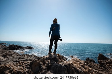Woman photographer enjoy the view on sunrise seaside rocks - Powered by Shutterstock