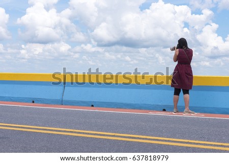 Woman photographer making a shot and beautiful sky