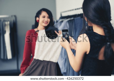 Woman photographing her friend trying on dress