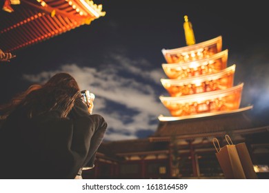 A woman photographing the Pagoda at Sensō-ji temple in the neighborhood of Asakusa in Tokyo