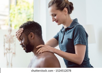 Woman Physical Therapist Massaging Young Black Man Holding His Head