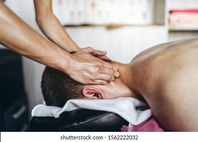 A woman physiotherapist doing neck massage for a man in the medical office. Closeup of hands doing massage.