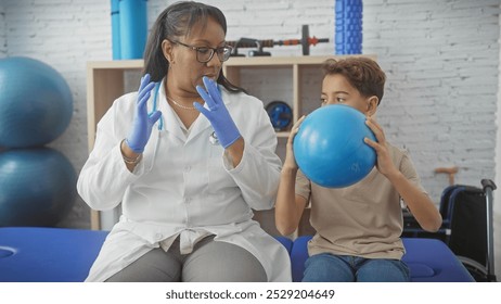 A woman physiotherapist instructs a young boy during a therapy session with a blue exercise ball in a rehab clinic. - Powered by Shutterstock