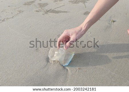 Woman pick the plastic cup on sea sand