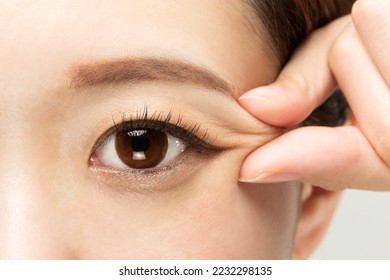 A woman is picking the corner of her eye.