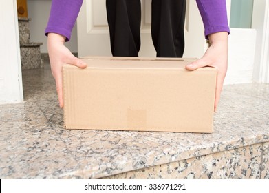 Woman Picking Up The Delivering A Package From The Entrance Of Her Home