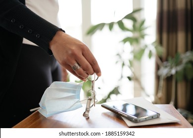 Woman Picking Up Keys And Face Mask Ready To Leave Home. New Normal Concept