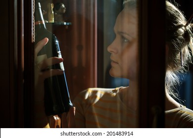 Woman Picking Out Wine Bottle From Liquor Cabinet