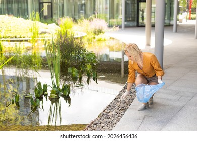 Woman Picking Up Plastic Household Waste In Park