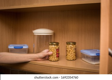 Woman Picking Up A Pot Of Chickpeas From The Kitchen Pantry