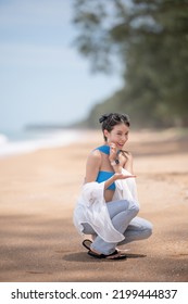 Woman Picking Up Shells And Holding Them In Hand On The Beach.