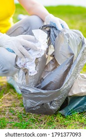 Woman Picking Up Used Paper In A Summer Park. Volunteer And Ecology Concept