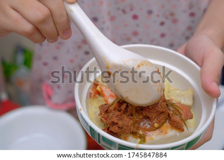A woman picks a piece of "rendang"beef  with a spoon
