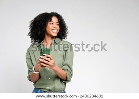 The woman is pictured in a candid moment, looking away from her phone with a natural and relaxed smile, evoking a sense of ease and authentic interaction