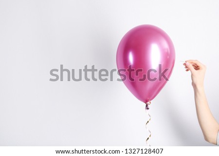 Woman piercing balloon with needle on white background, closeup