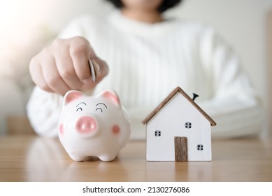 Woman With Piggy Bank And Future House Concept Of Saving And Loan Money For House. To Rent Or Buy New House With Saving Money In Piggy Bank.