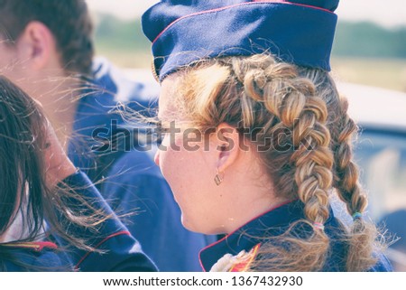 Woman with pigtails in uniform in a forage-cap. Rear view