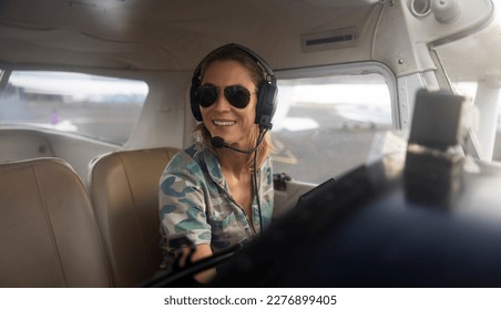 Woman pilot in military uniform pre-flight checking inside on a small aviation airplane. Flight pre-check inspection. - Powered by Shutterstock