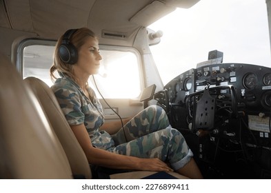 Woman pilot in military uniform pre-flight checking inside on a small aviation airplane. Flight pre-check inspection. - Powered by Shutterstock