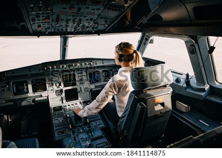 Woman pilot sitting in aircraft cockpit, flying the plane.